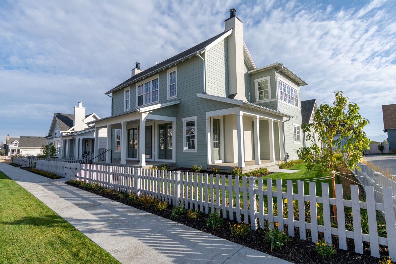 Window replacement in Olds: two-storey house with a white picket fence along the sidewalk