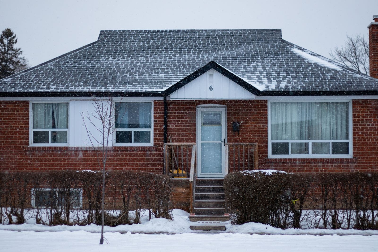 Window replacement in Ponoka: brick bungalow with white windows after a snowfall