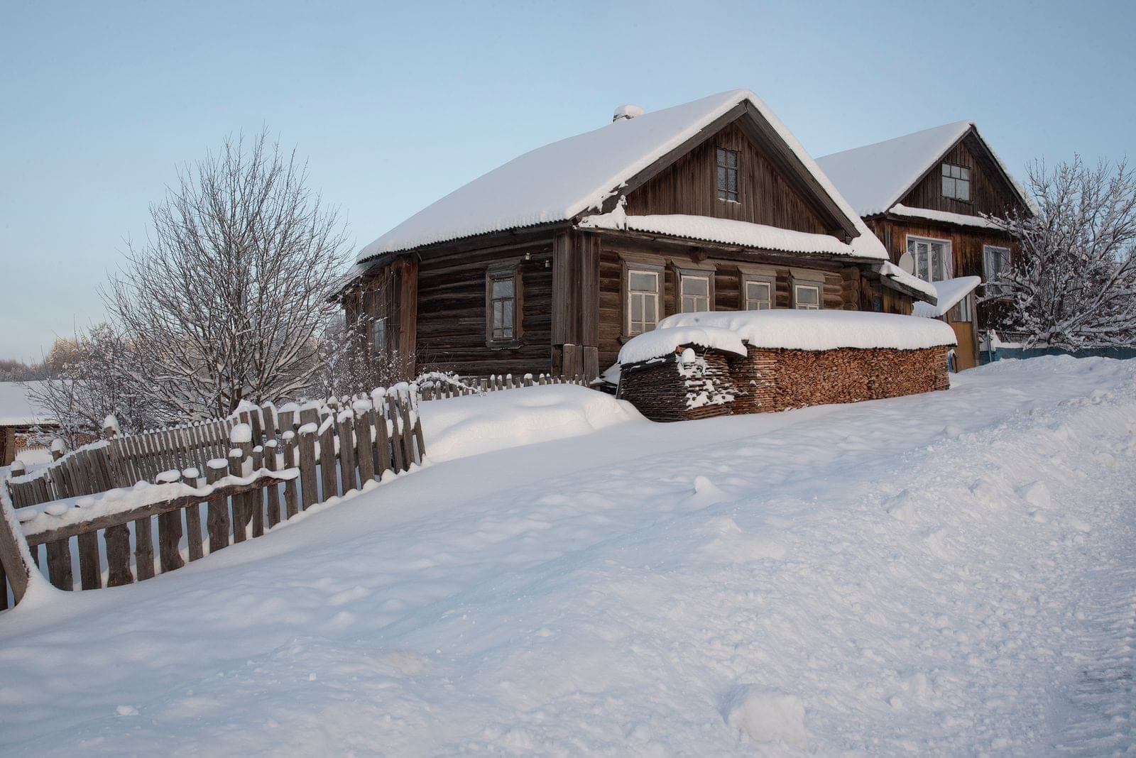 Window replacement in Rocky Mountain House: log house in deep snow with a wood fence